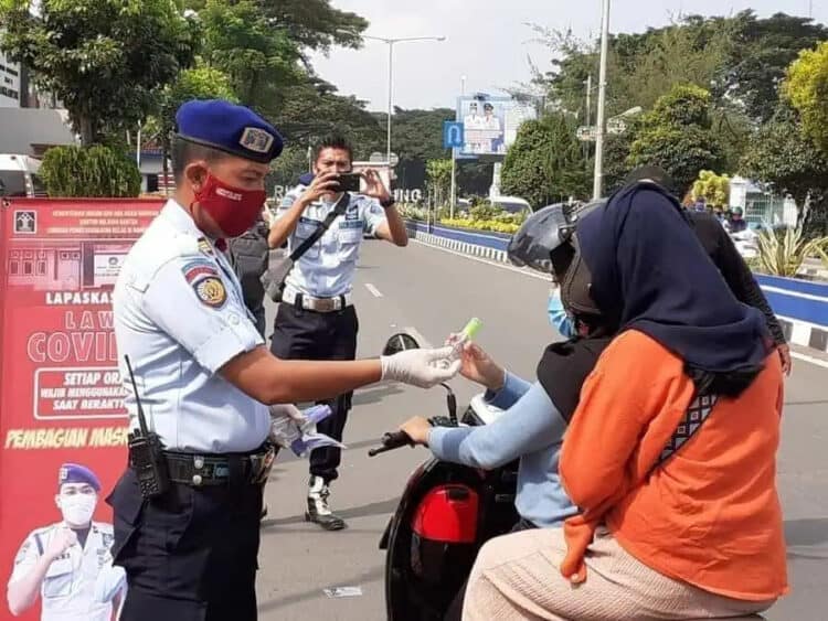 BAGIKAN MASKER DAN HAND SANITIZER: Budi Riswanto saat membagikan masker dan hand sanitizer kepada pengguna jalan, di depan Lapas Klas III Rangkasbitung, Kamis (23/4). (MULYANA/SATELIT NEWS)