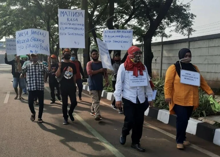 BAWA POSTER: Keluarga HG berjalan sembari membawa poster berisi tuntutan menuju Kejari Tangerang, Rabu (12/8). (IRFAN/SATELIT NEWS)