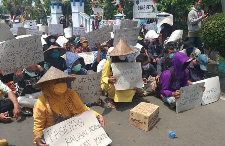 BENTANGKAN KECAMAN: Ratusan petani Sindangresmi duduk di jalanan depan kantor Distan Pandeglang, sambil membentangkan kencaman dan berorasi pada saat melakukan unjuk rasa, Selasa (8/9). (NIPAL/SATELIT NEWS)