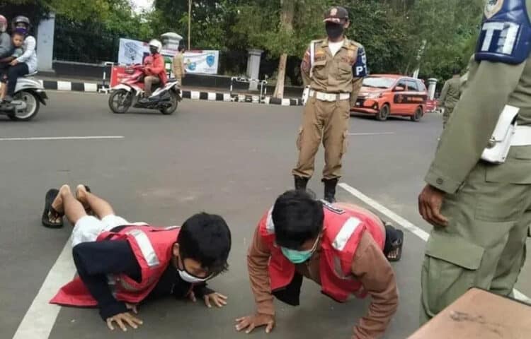 BERIKAN SANKSI: Petugas Gabungan Penegakan Perbup 55 Tahun 2020, sedang memberikan sanksi kepada warga yang melanggar protokol kesehatan, saat menggelar razia di Alun-alun dan Pasar Pandeglang, Minggu (13/9). (NIPAL/SATELIT NEWS)