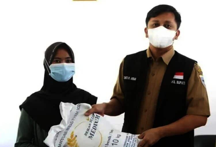SERAHKAN BANTUAN BERAS–Wabup Pandeglang, Tanto Warsono Arban, secara simbolis menyerahkan bantuan beras kepada seorang KPM, di Aula Kantor Kecamatan Sindangresmi, Senin (26/7/2021). (ISTIMEWA)