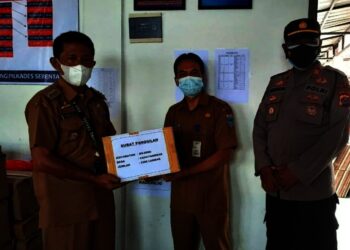 PENYERAHAN LOGISTIK PILKADES–Kabid Pemdes DPMPD Pandeglang, Asep Permana (tengah), didampingi pihak kepolisian, secara simbolis menyerahkan logistik Pilkades ke Camat Bojong, Endin Haerudin (kiri), di Aula DPMPD Pandeglang, Senin (2/8/2021). (NIPAL SUTIANA/SATELITNEWS.ID)