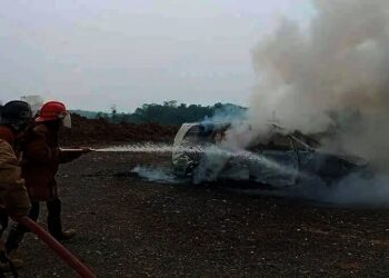 Petugas Damkar sedang memadamkan api yang sempat membakar mobil, akibat dipicu sebuah laptop yang meledak. (ISTIMEWA)