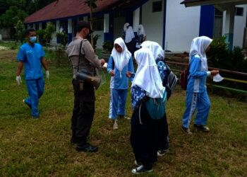 BAGIKAN MASKER–Jajaran personel Polsek Jiput, membagikan masker sambil mengimbau disiplin Prokes, di lapangan SMP Negeri 2 Jiput, Kamis (21/10/2021). (ISTIMEWA)