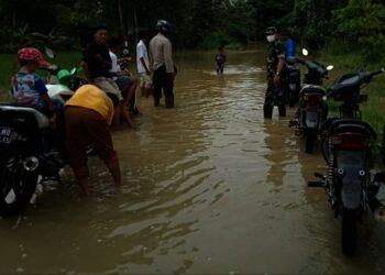 TERGENANG–Genangan air yang merendam jalur di wilayah Kecamatan Patia, dimanfaatkan warga untuk mencuci kendaraan, Senin (22/11/2021). (ISTIMEWA)