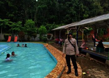 Personel Polsek Cibaliung sedang memberikan pengamanan dan imbauan Prokes, di tempat wisata kolam renang di wilayah Kecamatan Cibaliung, Senin (1/11/2021). (ISTIMEWA)