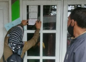 Petugas sedang memasang stiker di jendela rumah warga, di Kelurahan Pandeglang, yang sudah disutik vaksin Covid-19, Jumat (3/12/2021). (ISTIMEWA)
