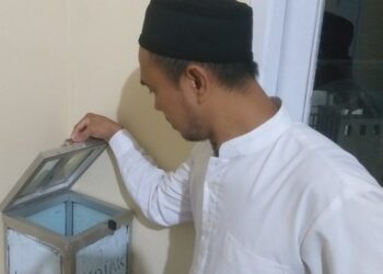 DIBOBOL–Ketua DKM Musala Al-Muqodas, Ustaz Maman sedang menujukan kondisi kotak amal usai dibobol maling, Senin (18/4/2022). (NIPAL SUTIANA/SATELITNEWS.ID)