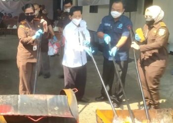 Kepala Kejari Pandeglang bersama para pihak lainnya, sedang memusnahkan barang bukti di halaman Kejari Pandeglang, Rabu (28/9/2022). (ISTIMEWA)