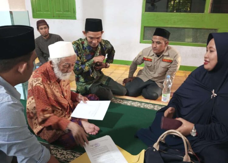 Abuya KH. Muhtadi Dimyati Cidahu, sedang membubuhkan tanda tangannya di secarik kertas, sebagai bukti merestui dan mendukung penuh kegiatan HSN 2022 di Pandeglang. (ISTIMEWA)