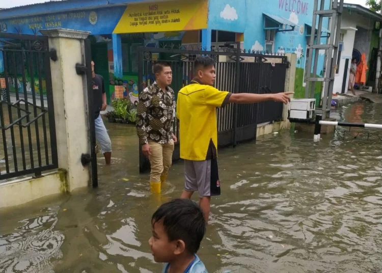 Camat Kibin, Babay Karnawi, melakukan pengecekan kondisi banjir yang merendam rumah warga. (SIDIK/SATELITNEWS.COM)