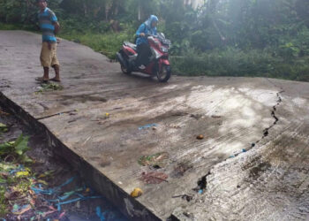 Pengendara motor, terlihat ekstra hati – hati saat melintas di Jalan Beton Kadupaeh – Kaduronyok, yang ambles, Minggu (8/1/2023). (ISTIMEWA)