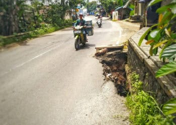 AMBROL TERGERUS ALIRAN SUNGAI–Badan jembatan Sungai Cikadueun, ambrol, lantaran tergerus arus sungai yang mengalir di bawahnya. Hal itu, membahayakan pengendara khususnya yang melintasi Jalan Raya Labuan – Pandeglang, Cikadueun, Kecamatan Cipeucang, karena jalur ini sewaktu-waktu bisa putus, Minggu (5/2/2023). (MARDIANA/SATELITNEWS.COM)