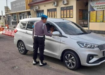 Seorang personel polisi sedang memeriksa kelengkapan dokumen pengendara, Senin (13/2/2023). (ISTIMEWA)