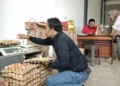 HARGA TELUR MELAMBUNG–Pembeli sedang memilah telur ayam, yang bakal dibelinya, di salah satu penjual telur di Pasar Badak Pandeglang. (DOKUMEN/SATELITNEWS.COM)