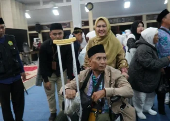 LEPAS CALHAJ–Bupati Pandeglang Irna Narulita, sedang mendorong jemaah Calhaj yang menggunakan kursi roda, keluar dari Aula Pendopo hingga masuk ke dalam bus, Minggu (28/5/2023). (ISTIMEWA)