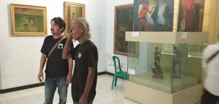 MELIHAT LUKISAN–Gebar Sasmita, sedang menunjukkan karya seni lukisnya saat Pameran Tunggal, di Gedung Bale Budaya, Dinas Pariwisata dan Kebudayaan (Disparbud) Kabupaten Pandeglang. (MARDIANA/SATELITNEWS.COM)