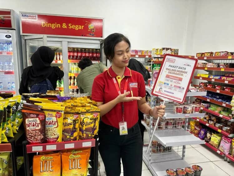Seorang karyawan minimarket menunjukkan promo di tokonya. (ISTIMEWA)