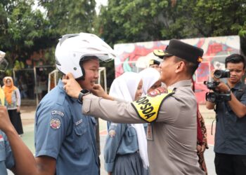 Wakapolda Banten kenakan helm kepada warga, sebagai bentuk sosialisasi pentingnya berkendara mengenakan helm. (ISTIMEWA)