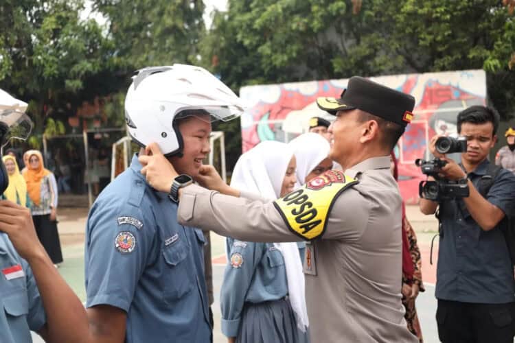 Wakapolda Banten kenakan helm kepada warga, sebagai bentuk sosialisasi pentingnya berkendara mengenakan helm. (ISTIMEWA)
