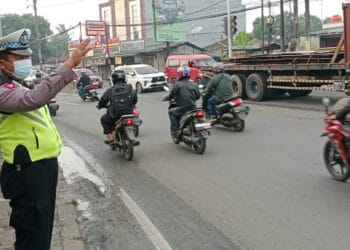 ATUR LALU LINTAS: Seorang anggota Polisi sedang mengatur arus lalu lintas (Lalin) di Jalan Raya Serang, Desa Cibadak, Kecamatan Cikupa. (DOK/SATELIT NEWS)