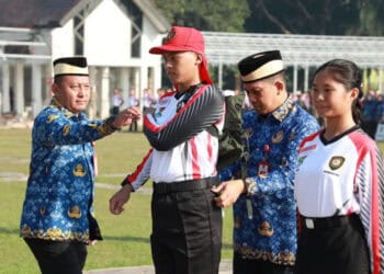 SIMBOLIS: Pj Bupati Andi dan Kepala Badan Kesbangpol Kabupaten Tangerang Rudi Lesmana, secara simbolis menyematkan perlengkapan training center, tanda dibukanya TC Anggota Paskibra Kabupaten Tangerang di sela-sela upacara, Rabu (17/7/2024). (ISTIMEWA)