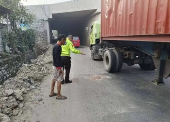 Seorang petugas kepolisian, tengah menunjukan lokasi terjadinya kecelakaan pengendara motor. (ISTIMEWA)