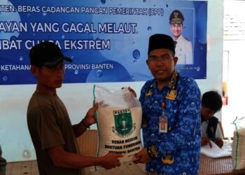 MENYERAHKAN BANTUAN : Kepala Dinas Ketahanan Pangan Banten, Nasir M Daud (kanan) menyerahkan bantuan beras CPP kepada warga Pulau Tunda. (ISTIMEWA)