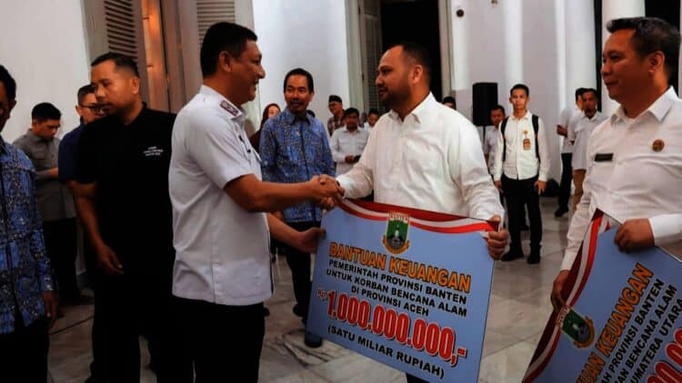 MENYERAHKAN BANTUAN : Kepala BPBD Provinsi Banten Deden Apriandhi Hartawan (kiri), menyerahkan bantuan kemanusiaan dari Pemprov Banten, secara simbolis, Rabu (3/12/2025) malam. (ADIB FAHRIE/SATELITNEWS.COM)