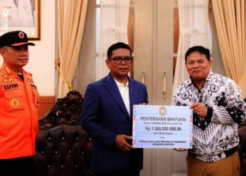 MENYERAHKAN BANTUAN : Ketua PGRI Banten Jamaludin (kanan), menyerahkan bantuan secara simbolis kepada Gubernur Banten Andra Soni. (ISTIMEWA)