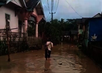 Seorang warga Desa Idaman, Kecamatan Patia Kabupaten Pandeglang, menyusuri genangan air sambil hendak pulang ke rumahnya, Rabu (17/11/2025). (ISTIMEWA)