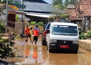 MEMBERISHKAN MATERIAL BANJIR : Personel BPBD Banten, membersihkan sisa material banjir. (ISTIMEWA)