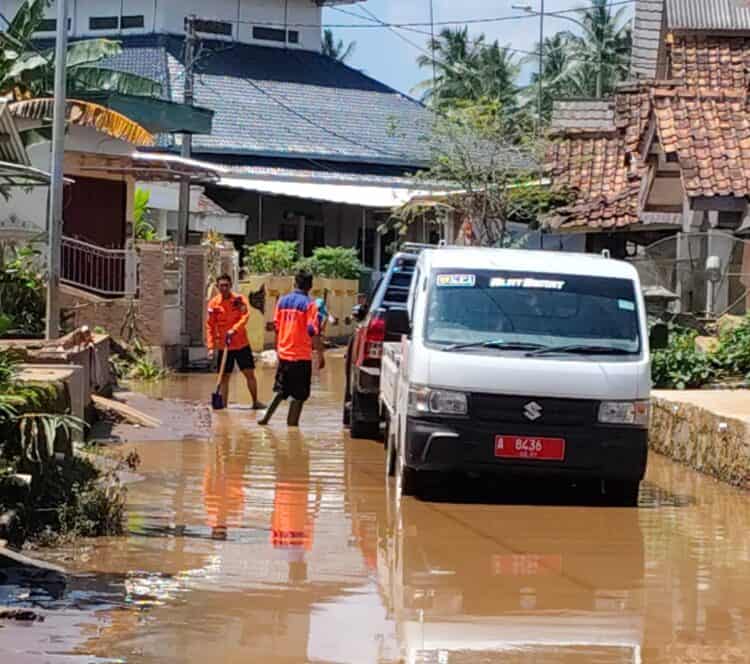 MEMBERISHKAN MATERIAL BANJIR : Personel BPBD Banten, membersihkan sisa material banjir. (ISTIMEWA)