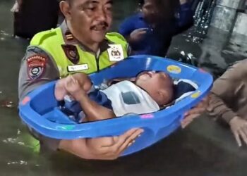 MENGEVAKUASI ANAK : Personel Polres Cilegon Polda Banten, mengevakuasi seorang anak yang rumah orang tuanya terendam banjir. (ISTIMEWA)