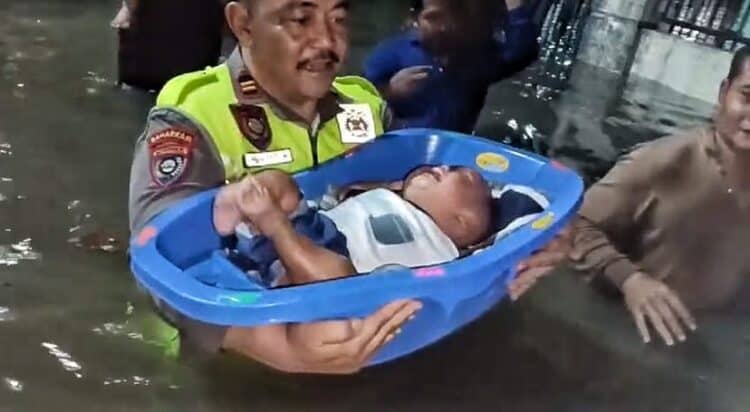 MENGEVAKUASI ANAK : Personel Polres Cilegon Polda Banten, mengevakuasi seorang anak yang rumah orang tuanya terendam banjir. (ISTIMEWA)