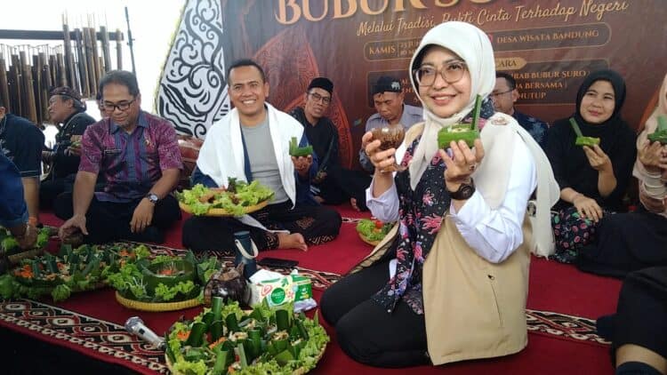 FESTIVAL BUBUR SURO - Bupati Pandeglang Raden Dewi Setiani, menunjukkan bubur yang sudah dimasak, saat menghadiri Festival Bubur Suro Desa Bandung, Kecamatan Banjar, Kabupaten Pandeglang, Kamis (25/6/2026). (MARDIANA/SATELITNEWS.COM)
